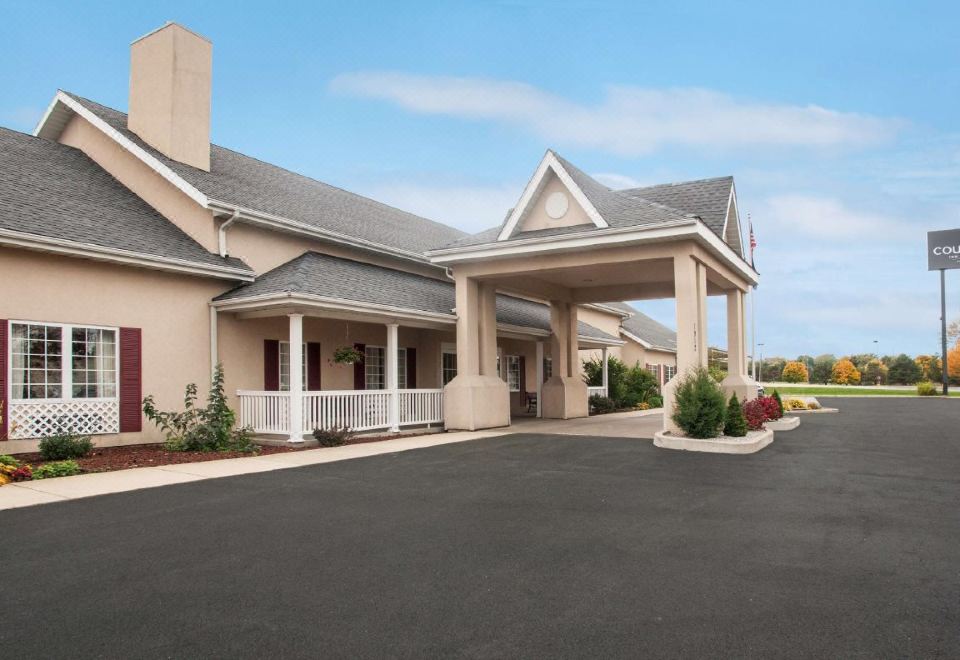 a large building with a covered entrance and a parking lot in front of it at Country Inn & Suites by Radisson, Kalamazoo, MI