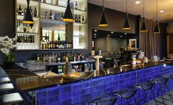 a modern bar with a blue and black color scheme , featuring a long counter with several bottles and glasses at Mantra Albury Hotel