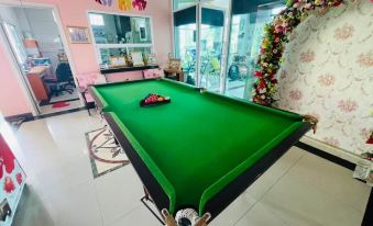 a billiards table in a living room , with a cat lying on the table and flowers adorning the walls at The Linux Garden Hotel