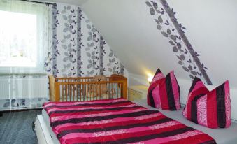 a cozy bedroom with a large bed , a crib , and a bathroom , decorated with white walls and black patterned wallpaper at Mary