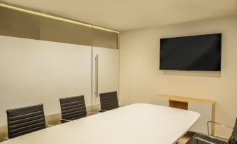 a conference room with a white table and chairs , a large screen on the wall , and wooden desk at Fiesta Inn Express Queretaro Constituyentes