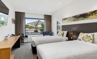 a modern hotel room with two beds , a couch , and a window offering a view of the outside at Quality Hotel Rules Club Wagga
