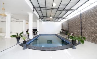 an indoor swimming pool with a large glass window , surrounded by white walls and a black - and - white tiled floor at Griya RW Family Guest House Redpartner
