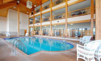 an indoor swimming pool surrounded by wooden walls , with several lounge chairs placed around the pool at Norfolk Lodge & Suites, Ascend Hotel Collection