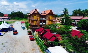 a wooden house with red roofs and balconies is surrounded by trees , cars , and a road at Kampong Pinang Sebatang