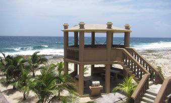 a beach house with a balcony and stairs leading up to it , surrounded by palm trees and the ocean at Kings Point
