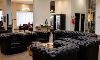 a large room with multiple black leather couches and chairs arranged in rows , creating a cozy atmosphere at Maison Hotel