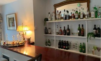 a well - stocked bar with various bottles and glasses , a mirror , and a couch in the background at Lydgate House Hotel