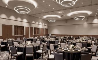 a large conference room with round tables and chairs set up for a formal event , possibly a wedding reception at Civic Hotel, Autograph Collection