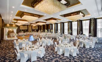 a large banquet hall with numerous tables and chairs set up for a formal event , possibly a wedding reception at Sheraton Grand Samsun Hotel