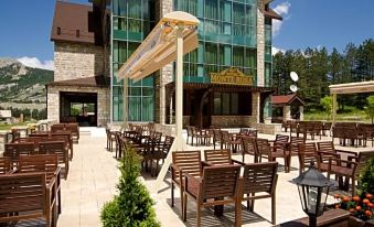 a large building with a glass facade and many windows is surrounded by wooden tables and chairs at Hotel Monte Rosa