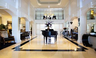 a large , white lobby with a black and white checkered floor , featuring a grand piano in the center at Inn at Pelican Bay