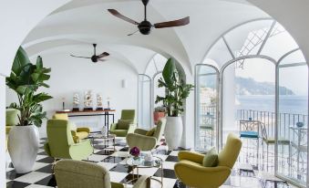 a modern living room with white walls , large windows , and black and white checkered floor , featuring various seating arrangements and decorative elements at Hotel Miramalfi