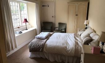 a cozy bedroom with a large bed , a dresser , and a window overlooking the outdoors at The Carew Arms