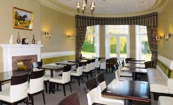 a large dining room with white chairs and black tables , set up for a meal at Hundith Hill Hotel