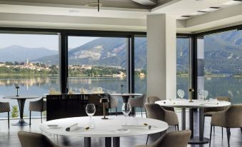 a restaurant with a view of a lake and mountains , featuring several dining tables and chairs at Bianca Relais