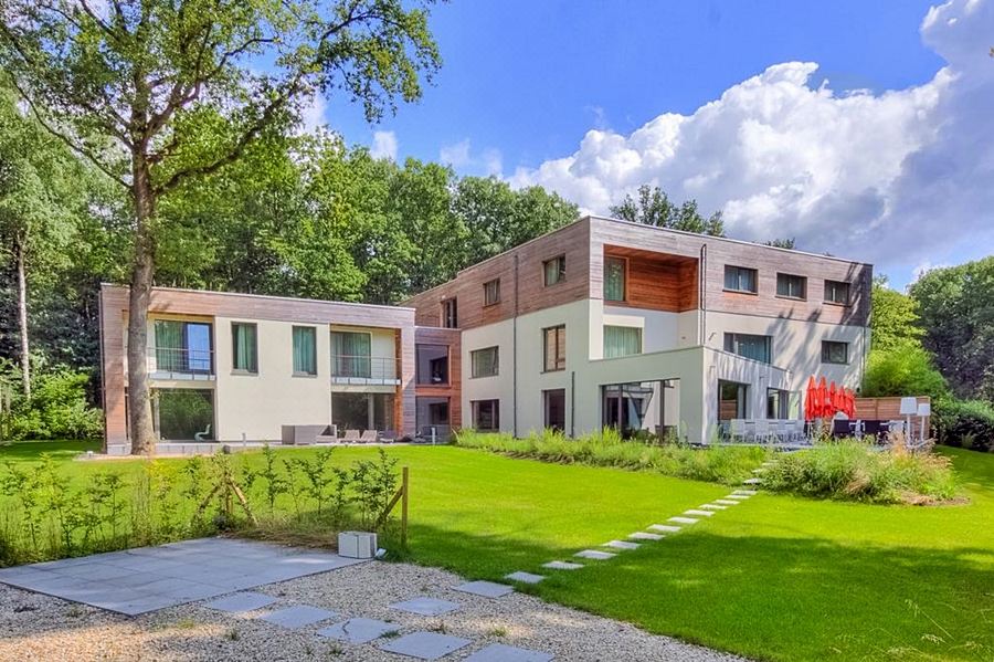 a modern apartment building surrounded by lush green grass and trees , with a clear blue sky in the background at Utopia Hotel - Art & Nature Hotel