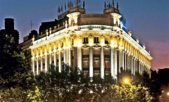 a large building with a fountain in front of it , surrounded by trees and other buildings at NH Madrid Nacional