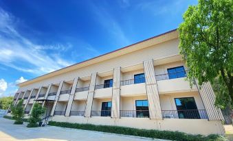 a large white building with a blue sky in the background and a tree in the foreground at MaiHom Villa