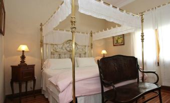 a bedroom with a four - poster bed and a black chair placed next to it , along with a bedside table and lamp at Plaza Hotel