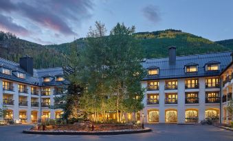 a large hotel with a stone entrance is surrounded by trees and mountains in the background at Grand Hyatt Vail