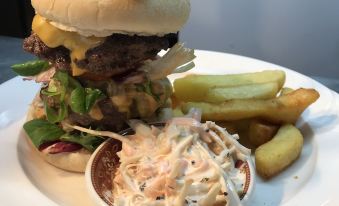 a large burger with fries and coleslaw is served on a plate , accompanied by a side of fries at The Old Pound Inn