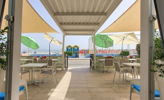 an outdoor dining area under a covered structure , with several tables and chairs set up for guests at San Marco