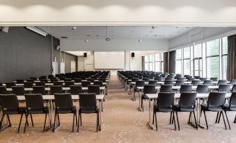 an empty conference room with rows of black chairs and a projector screen on the wall at Quality Hotel Entry