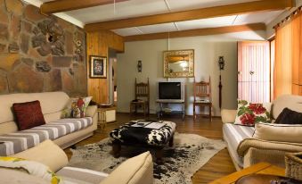 a cozy living room with wooden furniture , including a couch , chairs , and a coffee table at Morning Glory Cottages