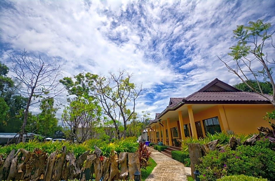 a beautiful house surrounded by lush greenery and a clear blue sky , with a path leading to it at Pimtara Beach Resort