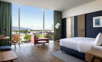 a hotel room with a king - sized bed , a couch , and a large window overlooking a beautiful view at Four Points by Sheraton Panoramahaus Dornbirn