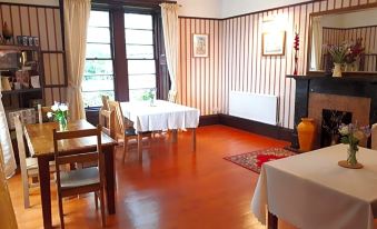 a dining room with wooden floors and red walls , featuring a table with white tablecloth and chairs at Rigg House B&B