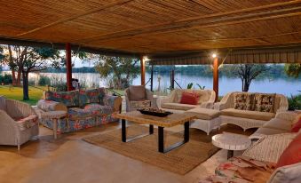 a cozy living room with various furniture , including a couch , chairs , and a coffee table , situated near a body of water at River View Lodge