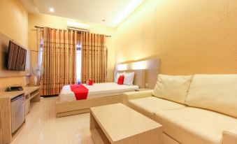 a modern hotel room with two beds , a couch , and a tv , all decorated in neutral colors at RedDoorz Near Candi Ratu Boko