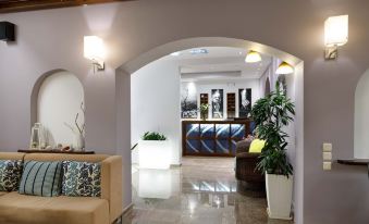 a modern living room with a couch , chairs , and potted plants under an arched doorway at Sofia Hotel