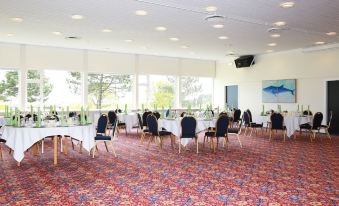 a large , empty room with a carpeted floor and multiple tables set up for a formal event at Hotel Marina
