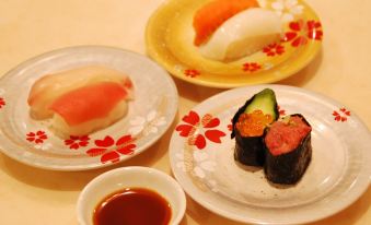 a table with three plates of sushi , one plate has a leaf design and another has an avocado slice and another has a roll at Fuji Matsuzono Hotel