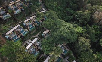 The top floor of the resort offers an aerial view of a forested area with trees and houses at Dinso Resort & Villas Phuket, Vignette Collection