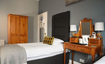 a cozy bedroom with a white bed , a black headboard , and a wooden dresser in the corner at The Labouring Man