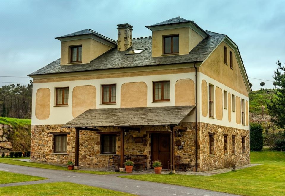 a large stone house with two chimneys on the side , surrounded by grass and trees at El Castro