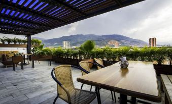 an outdoor dining area with a table and chairs , surrounded by greenery and overlooking a mountainous landscape at Hotel Perlatto