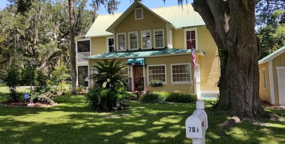 a yellow house with a green roof and a white mailbox in front of it at Dolan House B&B