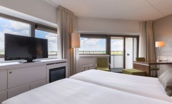 a hotel room with two beds , a television , and a window overlooking the city , as well as a window that offers a view of the at Leonardo Hotel Papendrecht