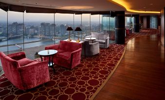 a large , modern hotel lobby with multiple couches and chairs arranged around a large window overlooking the city at Grand Nile Tower