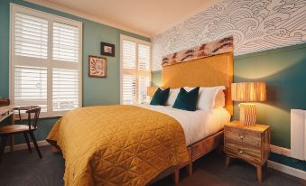 a bedroom with a large bed covered in yellow blankets , surrounded by green and white walls at The Old Success Inn