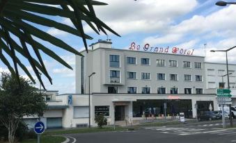 "a large white building with the words "" la grande hotel "" on top , located in a city street" at Le Grand Hotel
