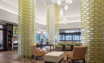 a spacious living room with various seating options , including couches , chairs , and a dining table at Hilton Garden Inn Akron