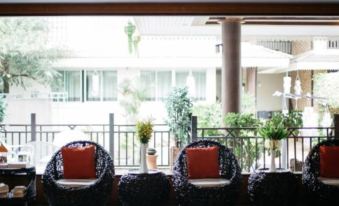 a black and white patio set with two chairs , a table , and potted plants , all situated in front of a building at Diamond Park Inn Chiangrai & Resort