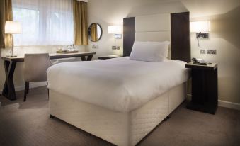 a large bed with white linens is situated in a hotel room next to a desk at New Place