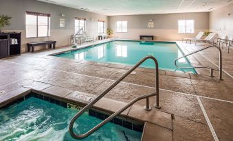 an indoor swimming pool with a diving board and water slides , surrounded by windows and tiled walls at Best Western Plus Williston Hotel  Suites